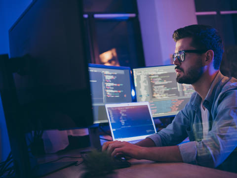 Software engineer surrounded by screens
